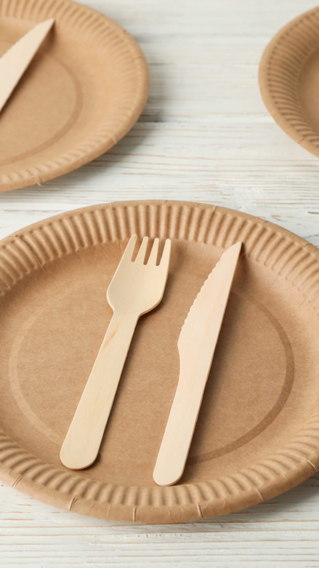 Flat lay with eco - friendly dishware on white wooden background. Disposable tableware